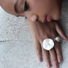 Model face and hand with flower ring.