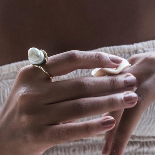 Big pearl ring on a hand.
