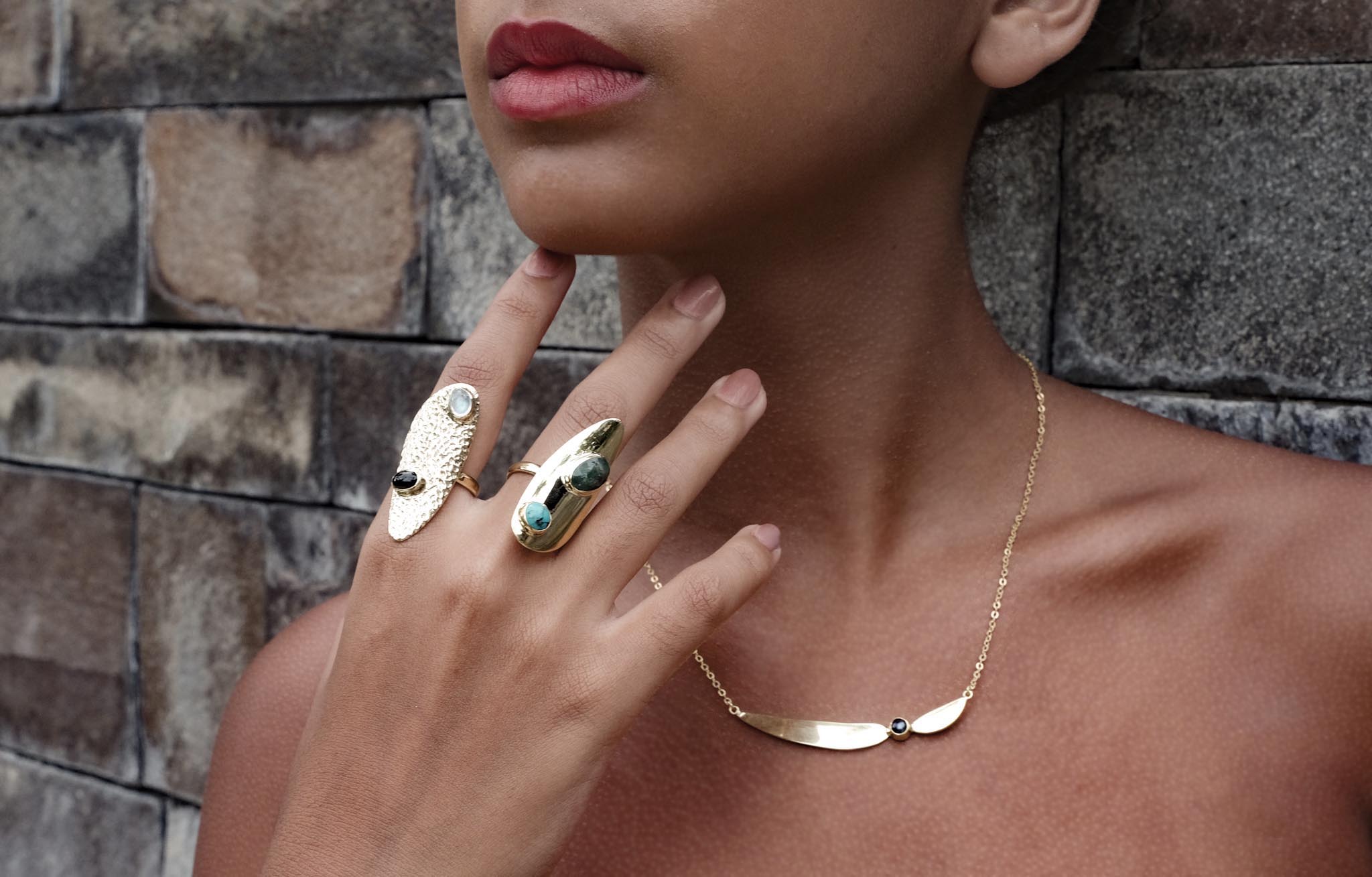 model wearing two rings and a necklace.